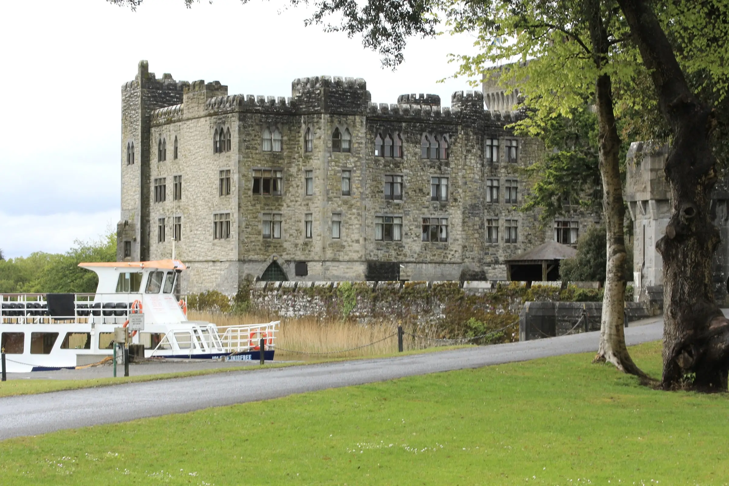 Ashford Castle on the shore of Lough Corrib, with a lake cruiser moored below its walls