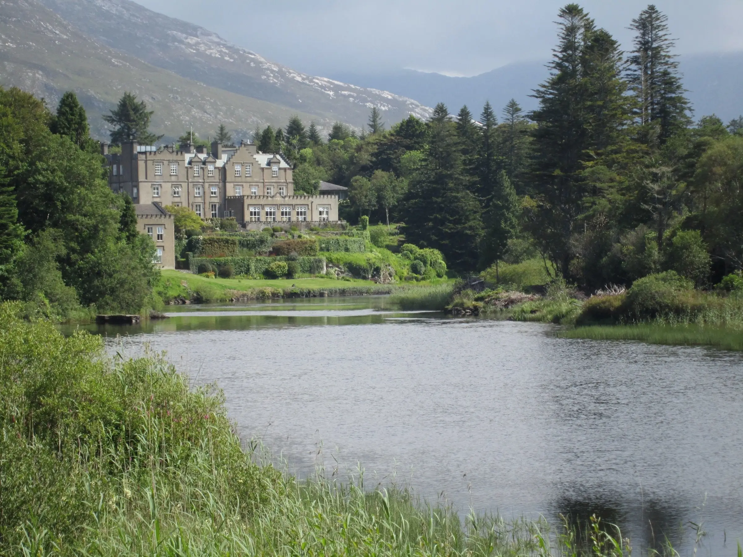 Ballynahinch Castle among the trees above the river in Connemara