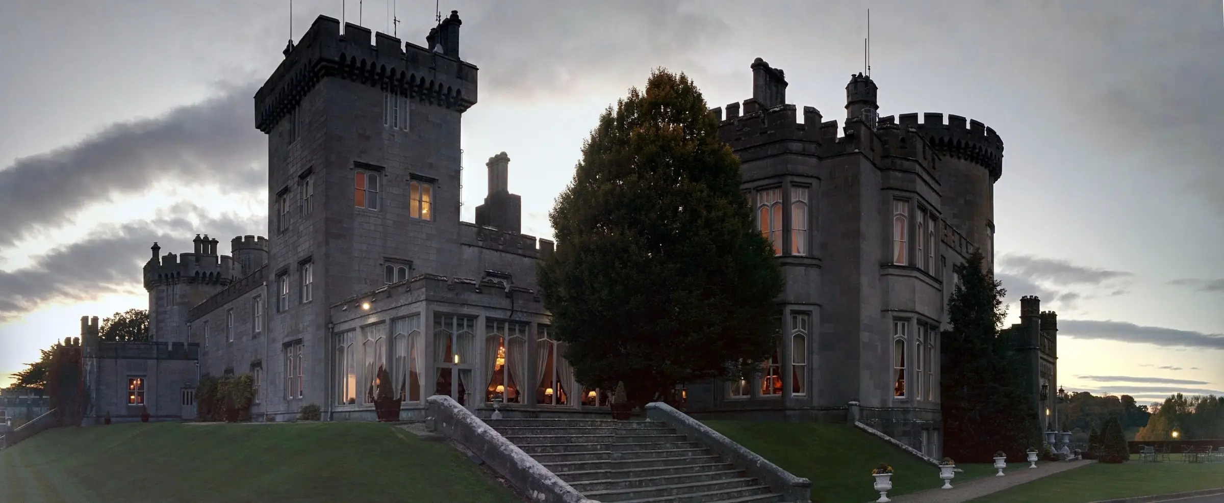 Dromoland Castle at dusk, its towers dark against the sky and its windows lit