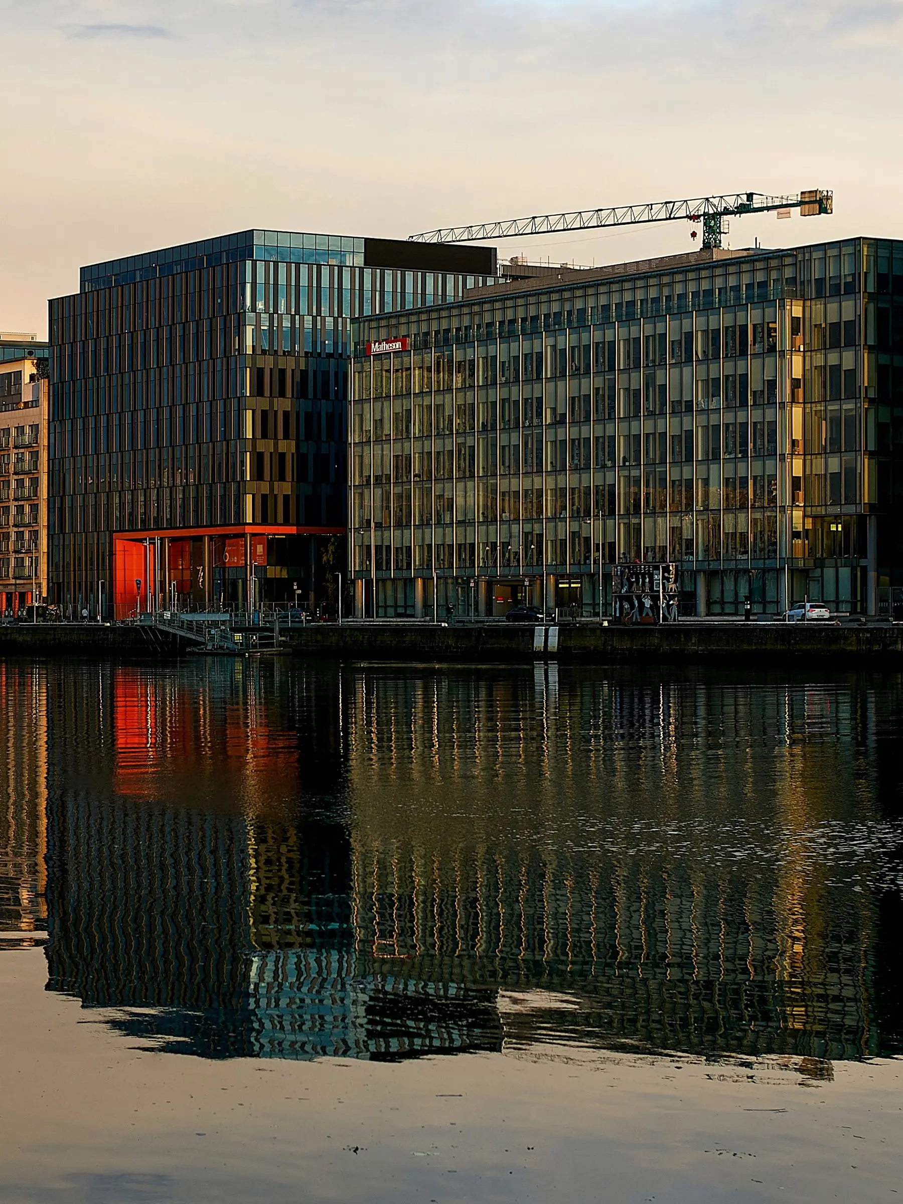 Glass office buildings on Sir John Rogerson’s Quay in Dublin’s Docklands, reflected in the Liffey at sunset