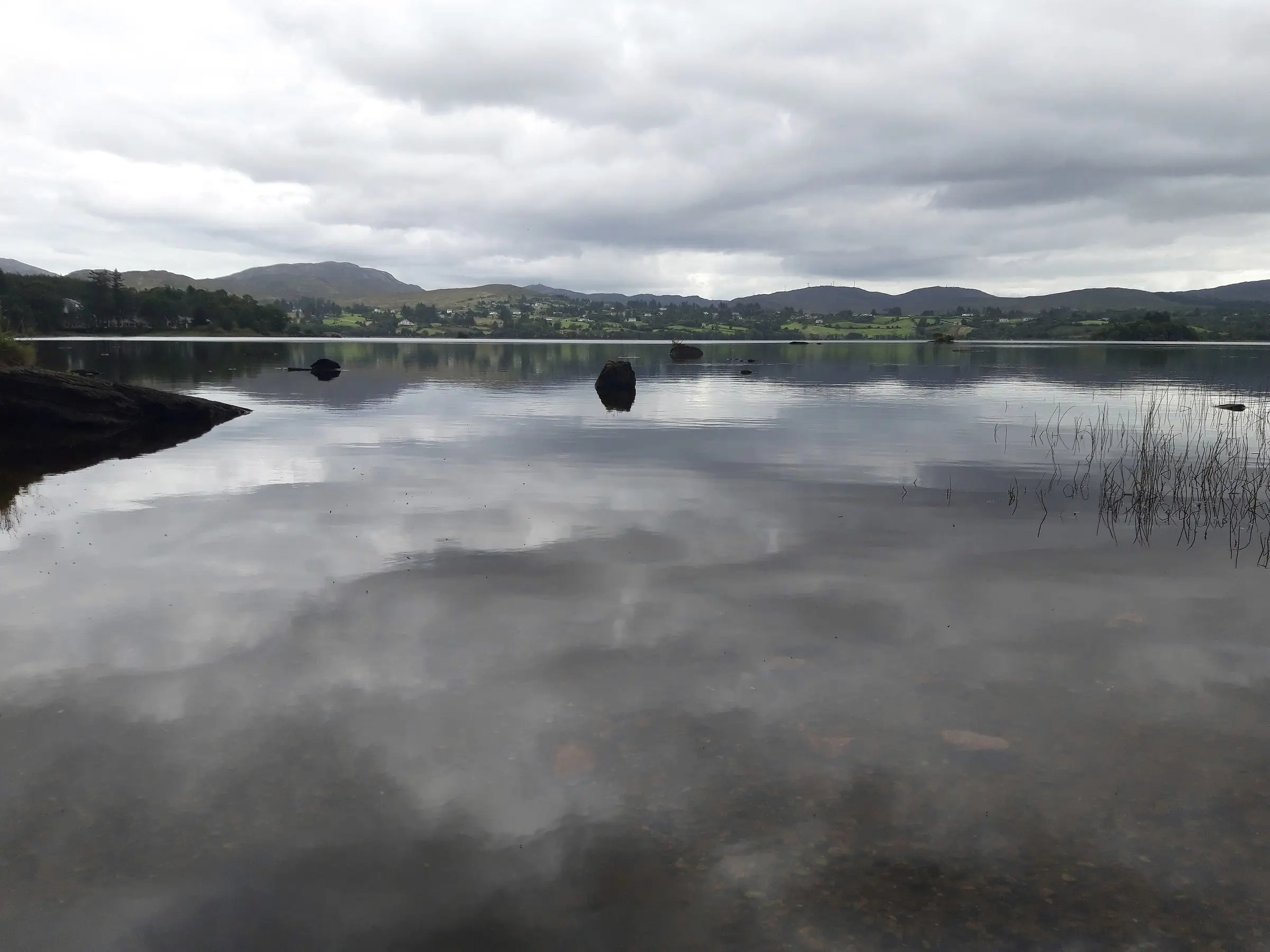 Lough Eske in County Donegal under a grey sky, with hills reflected in the still water