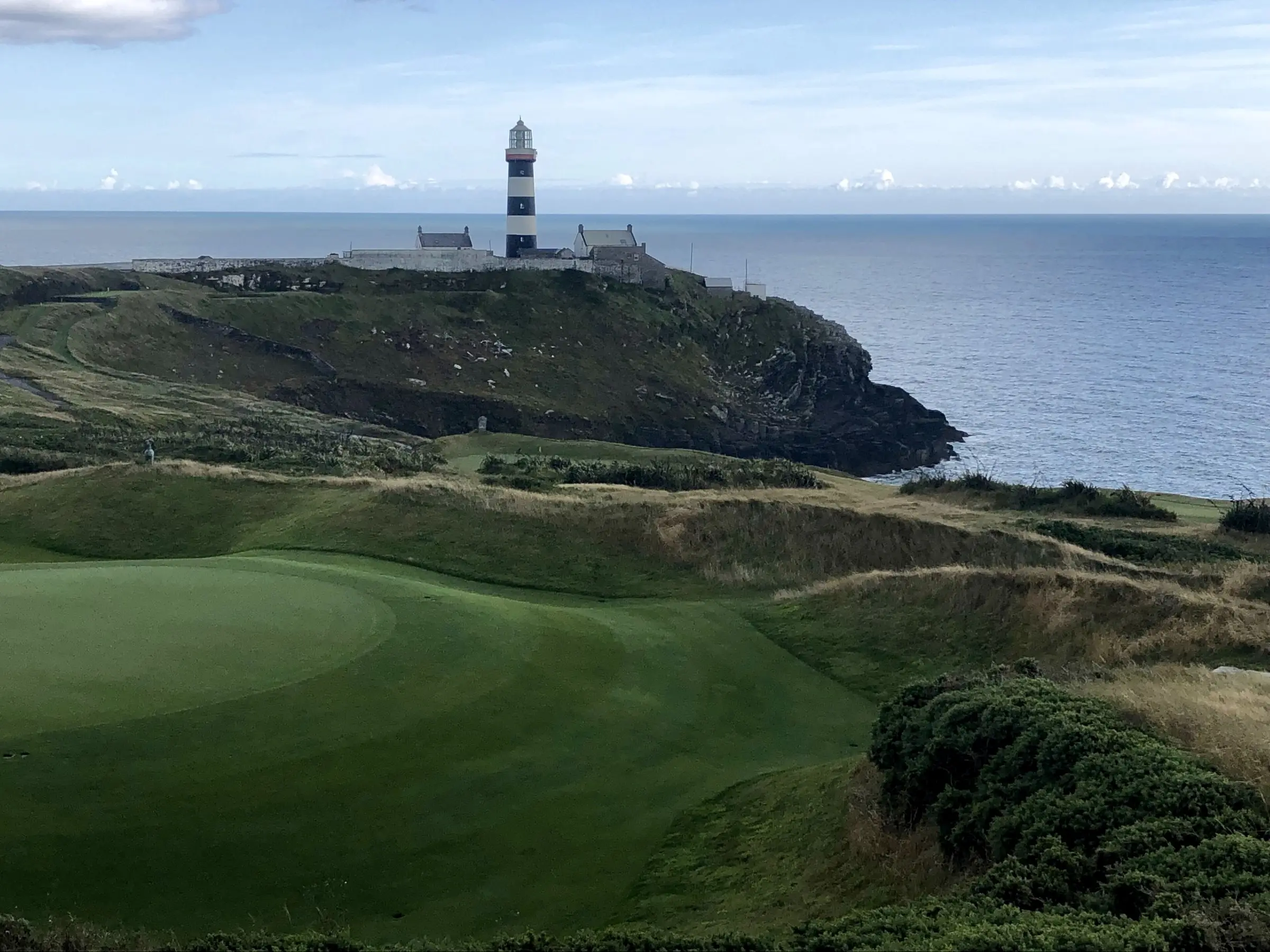 A green at Old Head Golf Links with the lighthouse on the headland and the Atlantic behind